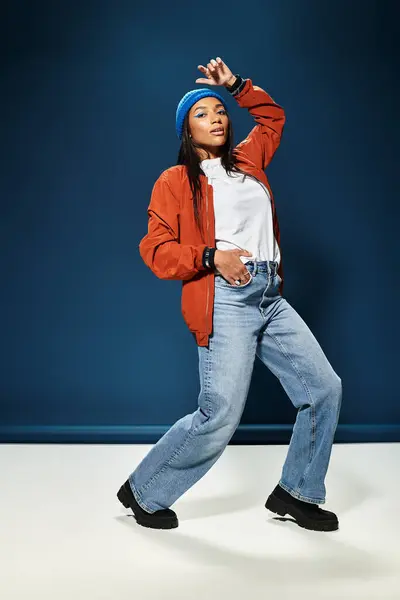 A young woman poses stylishly in her autumn outfit against a blue background. — Stock Photo