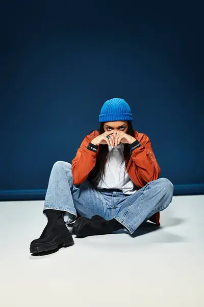 A young woman dressed in warm attire exudes style while seated on a smooth surface. — Stock Photo