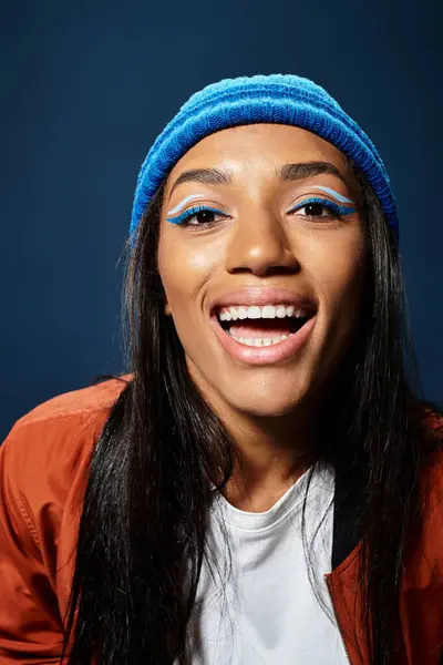 The young woman smiles brightly, showcasing her stylish warm attire against a dark backdrop. — Stock Photo