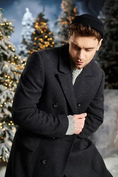 A dapper young man dressed in winter clothing stands thoughtfully among snowy trees, embracing the cheerful season. — Stock Photo