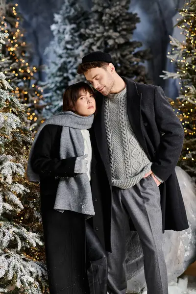 A happy couple enjoys a cozy moment near snow-laden pine trees, embracing the festive spirit of the season. — Stock Photo