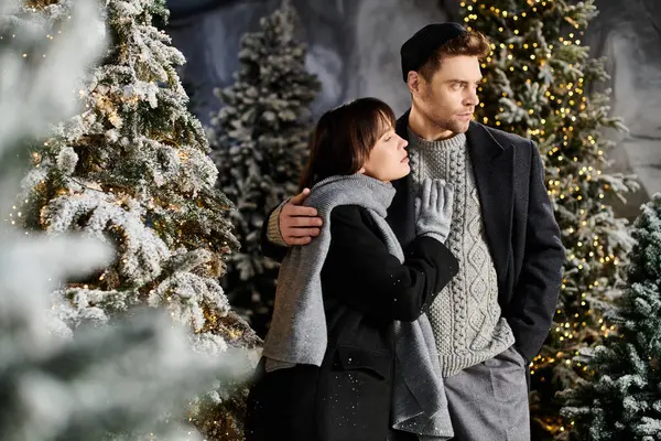 A couple embraces warmly, surrounded by snow-laden pine trees, joyfully celebrating the festive season. — Stock Photo
