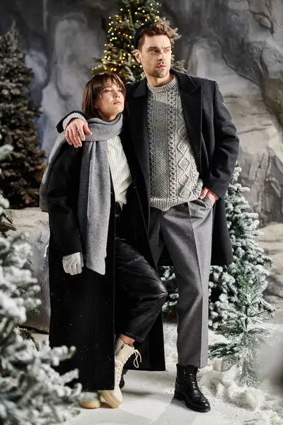 A charming couple enjoys each other company in cozy winter coats surrounded by snowy pine trees. — Stock Photo