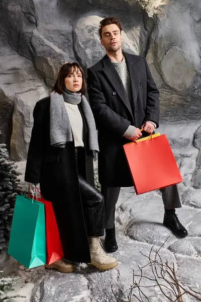 A lovely couple, wrapped in winter coats, shares a joyful moment by snow-laden pine trees during the holidays. — Stock Photo