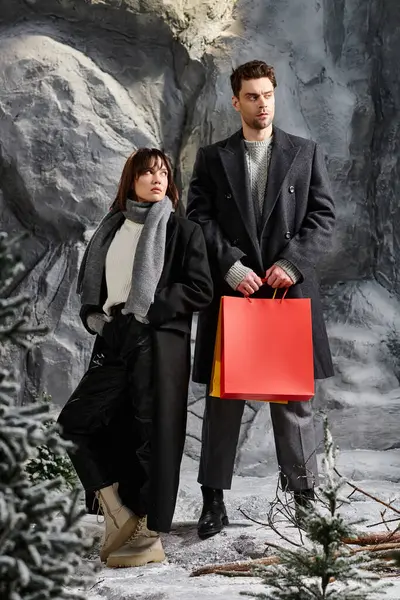 A couple stands together in a winter wonderland, dressed in cozy coats, celebrating the holiday spirit. — Stock Photo