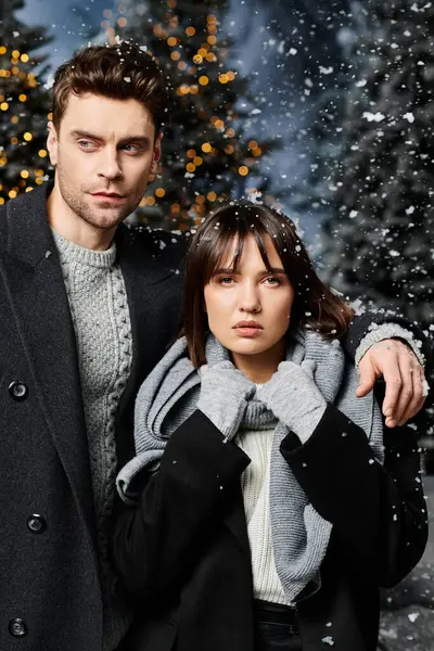 A charming couple bundled in warm coats embraces the festive spirit surrounded by snow-covered trees. — Stock Photo