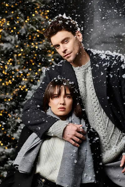 A beautiful couple in winter coats enjoys a snowy setting, celebrating the spirit of Christmas and New Year. — Stock Photo