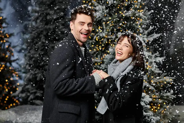 A lovely couple radiates happiness while celebrating the festive season among snow-covered trees. — Stock Photo