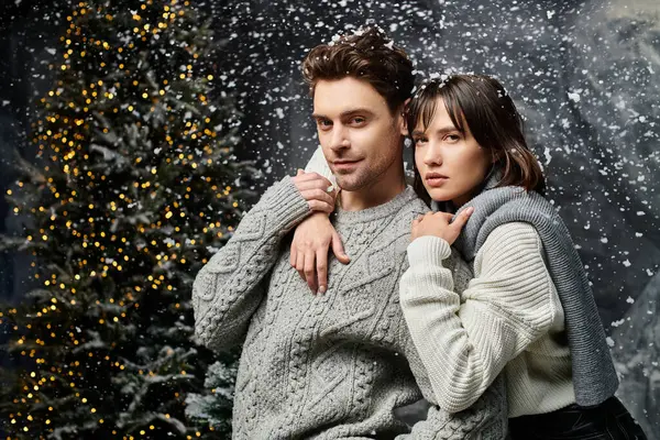 Um casal amoroso abraça calorosamente, comemorando a estação festiva em meio a abetos cobertos de neve. — Fotografia de Stock