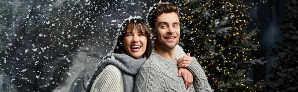 Wrapped in warmth, a couple shares laughter amid snowy fir trees, celebrating Christmas together with love. — Stock Photo