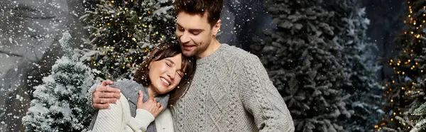 A loving couple shares a heartwarming moment near snow-covered fir trees, embracing the festive season. — Stock Photo
