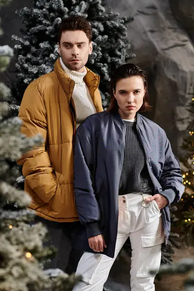 A couple bundled in winter jackets enjoys a snowy Christmas surrounded by beautiful pine trees. — Stock Photo