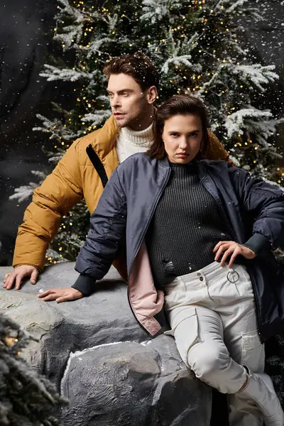A lovely couple enjoys a romantic moment together near snow-dusted pine trees in winter attire. — Stock Photo