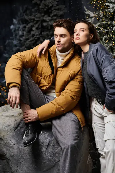 A couple embraces in winter jackets, surrounded by snow-laden pine trees during Christmas. — Stock Photo