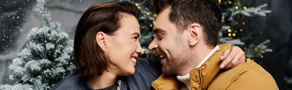 A couple embraces warmly, surrounded by snow-covered pine trees, celebrating the festive spirit of Christmas. — Stock Photo