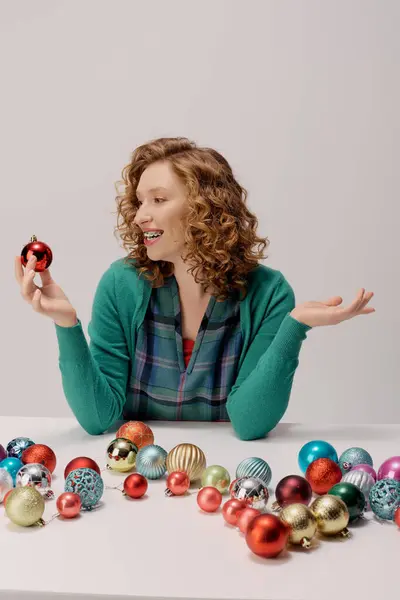 A young woman with curly hair smiles surrounded by festive decorations. — Stock Photo