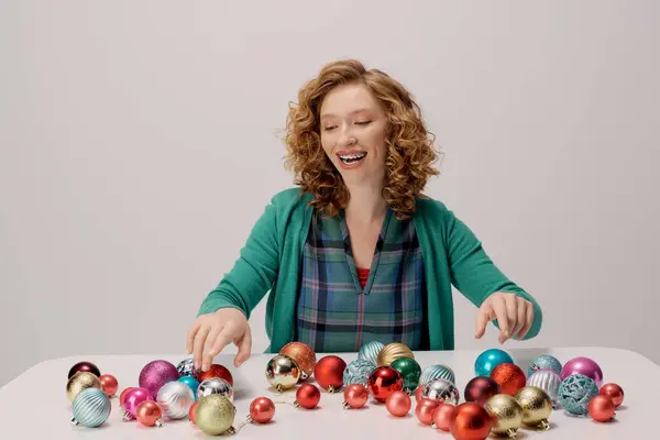 A young woman arranges vibrant ornaments while smiling, creating a festive atmosphere. — Stock Photo