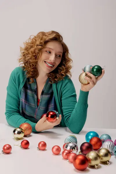 La joven sonríe mientras selecciona vibrantes adornos, preparándose para las celebraciones festivas. - foto de stock