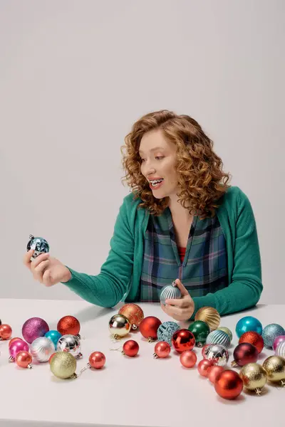 The young woman joyfully chooses bright ornaments, creating a festive vibe. — Stock Photo