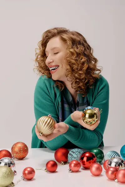 A young woman posing cheerfully while cheerfully holding shiny ornaments during the holiday season. — Stock Photo