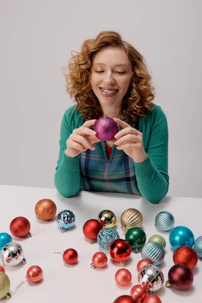 Laughing young woman explores vibrant ornaments while preparing festive gifts for a celebration. — Stock Photo