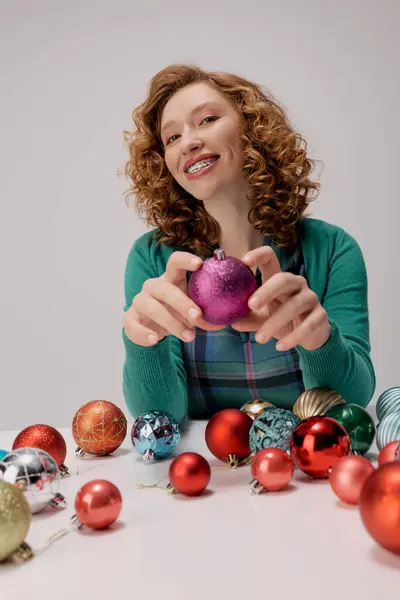 A young woman happily prepares vibrant decorations for a delightful holiday event at home. — Stock Photo