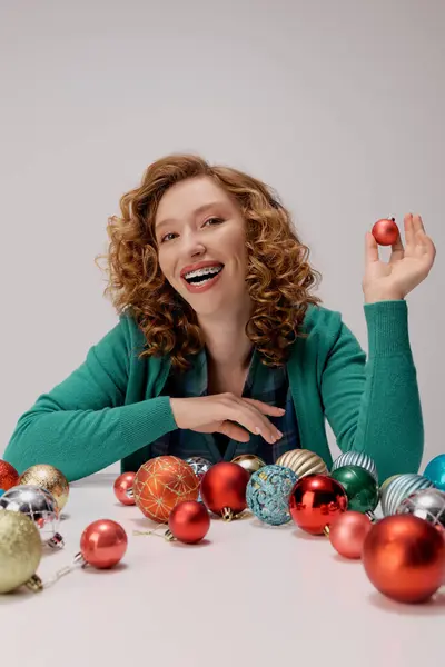 Eine junge Frau lächelt, während sie fröhlich posiert, umgeben von festlichem Schmuck für die Weihnachtszeit. — Stockfoto