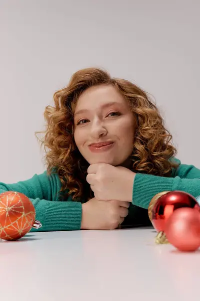 A cheerful young woman prepares gifts surrounded by holiday ornaments, embracing the festive spirit. — Stock Photo