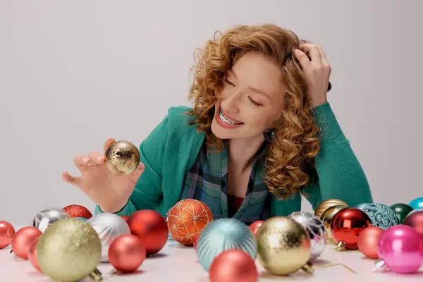 A young woman with curly hair smiles as she surrounded by vibrant ornaments. — Stock Photo
