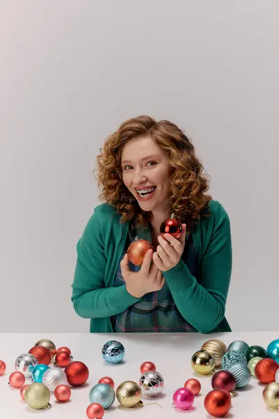A smiling young woman is posing cheerfully while surrounded by vibrant holiday decorations. — Stock Photo