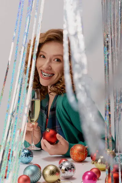 A young woman enthusiastically posing cheerfully, surrounded by shiny ornaments and sparkling decor. — Stock Photo
