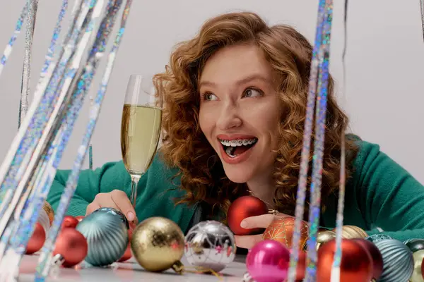 A young woman enjoys the festive spirit, posing cheerfully and surrounded by colorful decorations. — Stock Photo