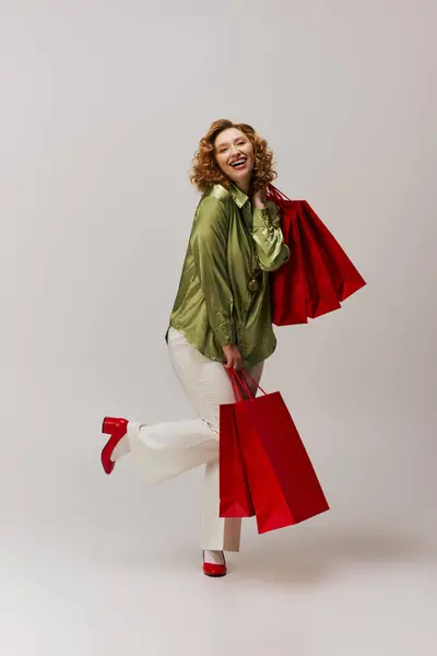 Uma jovem mulher feliz prepara presentes embrulhados, cercada por sacos de compras coloridos enquanto sorri. — Fotografia de Stock