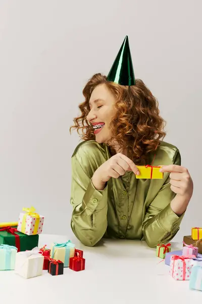 A young woman in a green shirt enjoys posing with colorful decorations. — Stock Photo