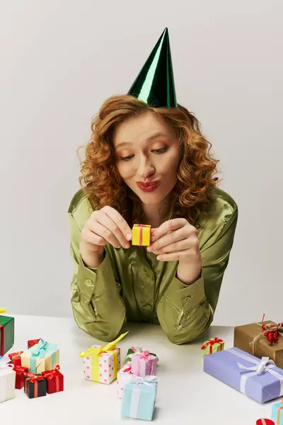 A jovem mulher em um chapéu de festa está posando cuidadosamente em uma mesa brilhante.. — Stock Photo