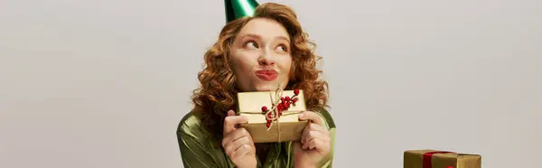 A young woman happily presents a beautifully wrapped gift, radiating excitement and joy. — Stock Photo