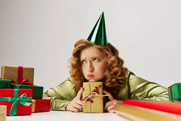 Una mujer joven aparece contemplativa mientras posa activamente presenta decoraciones coloridas. - foto de stock