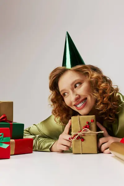 A happy young woman posing cheerfully, surrounded by colorful holiday decorations. — Stock Photo