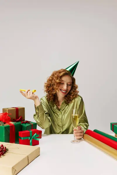 A young woman joyfully posing cheerfully with champagne and a party hat in a festive scene. — Stock Photo