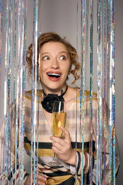 A cheerful young woman holds a drink, surrounded by colorful streamers and festive decor. — Stock Photo