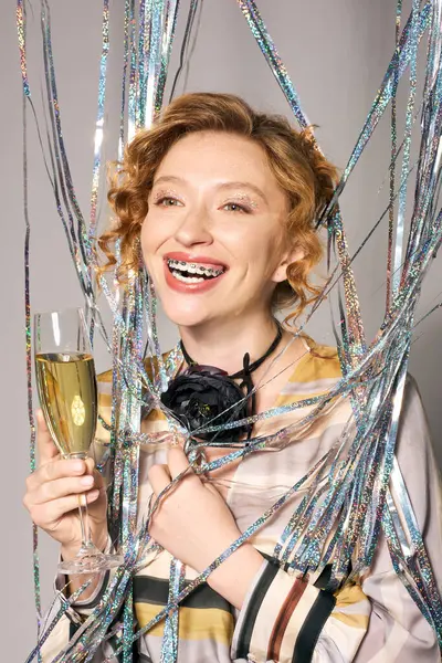A happy woman sips bubbly at a festive celebration with vibrant decorations. — Stock Photo
