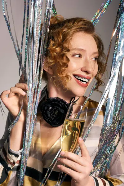 A joyful woman posing cheerfully amid shiny decorations, radiating celebration. — Stock Photo