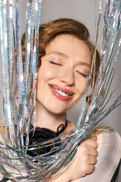 The young woman joyfully posing cheerfully, enchanted by shimmering decorations around her. — Stock Photo