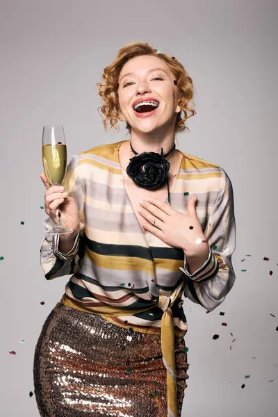 A cheerful woman celebrates with laughter, holding a drink surrounded by festive decorations. — Stock Photo