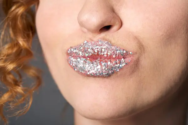 Una mujer joven adorna cuidadosamente sus labios con brillo brillante para un aspecto de maquillaje único. - foto de stock