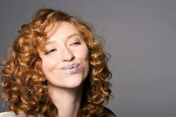 A cheerful young woman is posing cheerfully while showcasing her artistic flair and sparkling lips. — Stock Photo