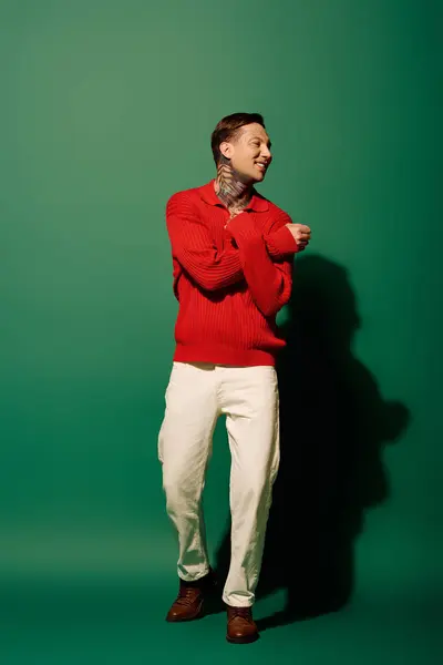 This young man showcases his tattoos while playfully moving against a green backdrop. — Stock Photo