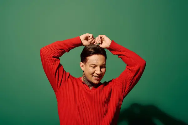 The young man smiles widely as he poses playfully with his hands raised above his head. — Stock Photo