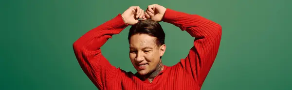 The young man in a red sweater showcases his tattoos while expressing happiness and energy. — Stock Photo