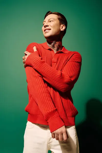 Un jeune homme présente des tatouages uniques tout en prenant une pose confiante dans un pull rouge vif. — Photo de stock